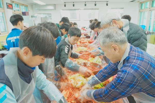 창녕 성산중학교 교직원과 학생들이 28일 '행복나눔 김장하기'에서 배추에 양념을 치대고 있다. /성산중