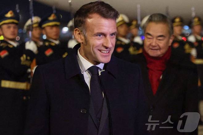 에마뉘엘 마크롱 프랑스 대통령이 3일 중국 베이징 국제공항에 도착해 왕이 중국 외교부장의 안내를 받아 차량으로 이동하고 있다. 2025.12.3 ⓒ AFP=뉴스1 ⓒ News1 김경민 기자