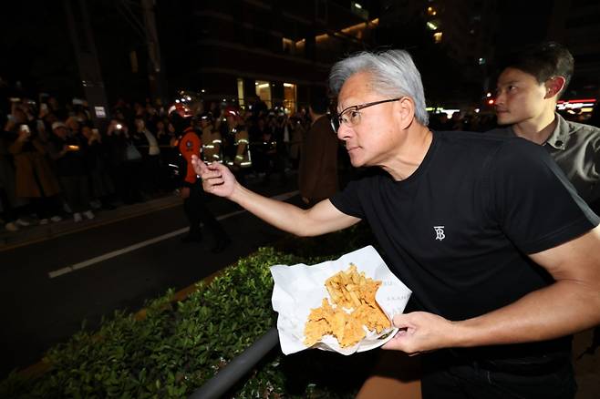 젠슨황 엔비디아 최고경영자가 지난 10월 30일 이재용 삼성전자 회장, 정의선 현대자동차그룹 회장과 서울 강남구 한 치킨 매장에서 회동 중 밖으로 나와 시민들에게 치킨 등을 나눠주고 있다./사진=뉴스1