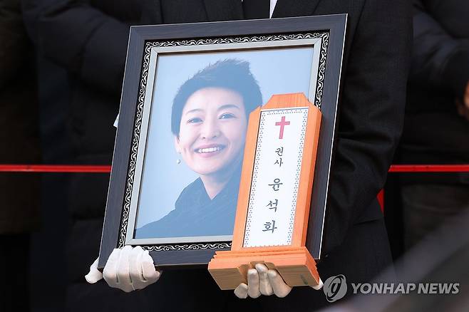 배우 윤석화 마지막 길, 대학로서 노제 (서울=연합뉴스) 강민지 기자 = 21일 서울 종로구 한예극장 앞에서 열린 배우 윤석화의 노제에서 유가족이 영정을 들고 있다. 2025.12.21 mjkang@yna.co.kr