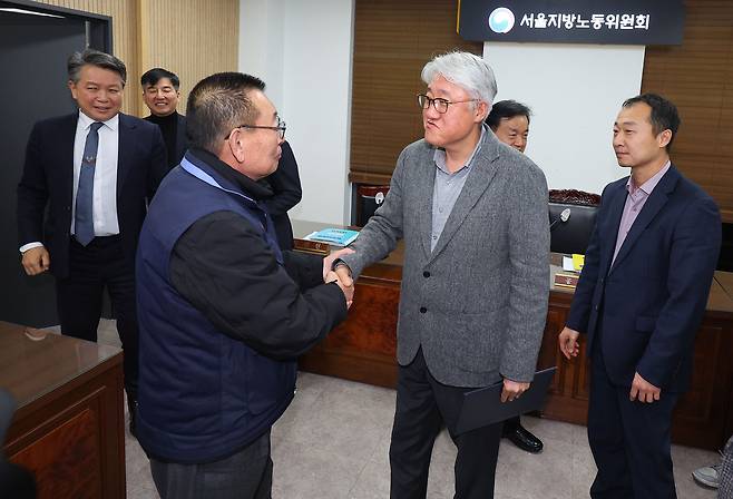Park Jeom-gon, chairman of the Seoul City Bus Workers Union (left) shakes hands with Kim Jung-hwan, head of the Seoul Bus Transport Association, after reaching a wage agreement at the Seoul Regional Labor Relations Commission in Yeongdeungpo-gu, South Korea, early Thursday. (Yonhap)