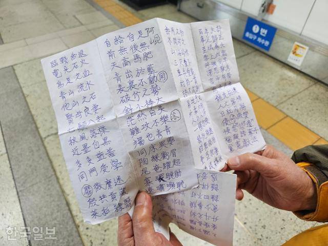 지난달 26일 지하철 1호선 서울역 역사에서 노인 고씨가 그동안 자신이 전철을 타며 한자로 적은 사자성어 메모를 펼쳐 보여주고 있다. 나광현 기자