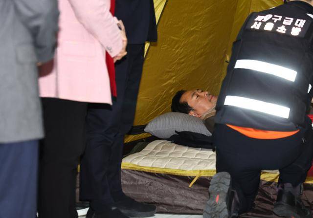장동혁 국민의힘 대표가 21일 국회 로텐더홀 단식 농성장에서 구급대원들에게 건강 진단을 받으며 누워 있다. 뉴시스