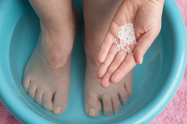 따뜻한 물 500cc에 소금 찻숟가락 2개 정도를 풀고 5~10분간 발을 담그면 효과적이다. 사진= 게티이미지뱅크