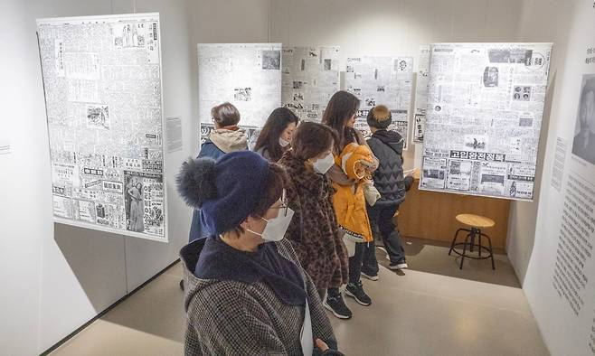 조선일보 아카이브 자료를 통해 이중섭의 발자취를 살펴보는 ‘쓰다, 역사로’ 섹션. 관람객들이 커다란 인쇄물 형태로 내걸린 옛 신문 지면을 살펴보고 있다. /이태경 기자