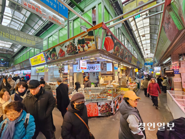 설 명절을 앞둔 12일 광명전통시장을 찾은 시민들이 좁은 시장 통로를 따라 오가고 있다.2026.2.12 /김지원기자 zone@kyeongin.com