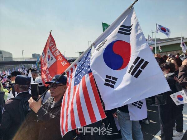 ▲지난해 4월 윤석열 전 대통령 탄핵심판 선고를 앞둔 가운데 열린 한남동 인근 탄핵반대 집회에서 참가자가 성조기와 태극기를 들고 있다. 사진=윤수현 기자