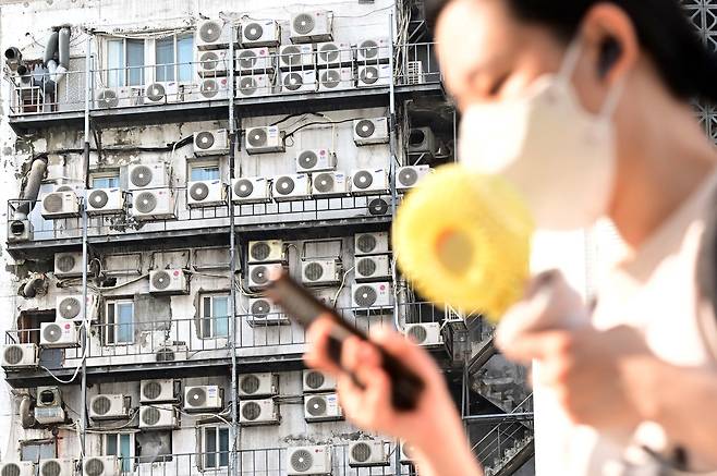 한 시민이 서울 중구 남대문 인근에 있는 건물 외벽에 줄지어 걸린 에어컨 실외기 앞을 지나가고 있다. 이상섭 기자