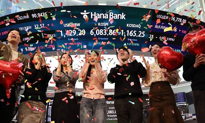 코스피가 사상 처음으로 6000을 돌파해 거래를 마친 25일 서울 중구 하나은행 딜링룸에서 딜러들이 기념 세리머니를 하고 있다. 연합뉴스