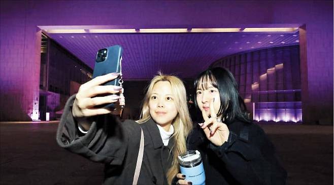 26일 서울 용산 국립중앙박물관에서 관람객들이 이날 처음 공개된 블랙핑크 새 음반 ‘데드라인’에 실린 노래를 듣고 있다. 박물관 관계자는 “우리 문화에 흥미를 느끼는 외국인들이 더 많이 찾아올 것”이라고 말했다. 아래 사진은 분홍색 조명으로 물든 박물관 건물 앞에서 블랙핑크 팬들이 셀카를 찍는 모습./고운호 기자