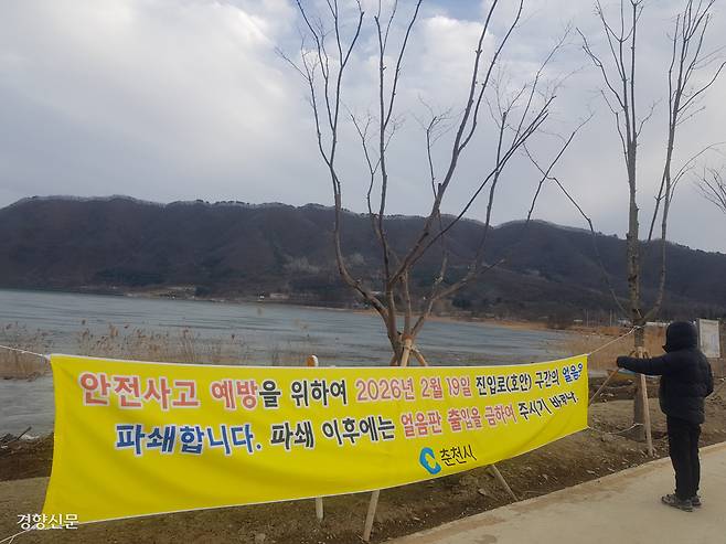 26일 오후 북한강 상류인 강원 춘천시 사북면 신포리 얼음낚시터를 찾은 한 시민이 ‘얼음판 출입금지’가 적힌 현수막을 살펴보고 있다.