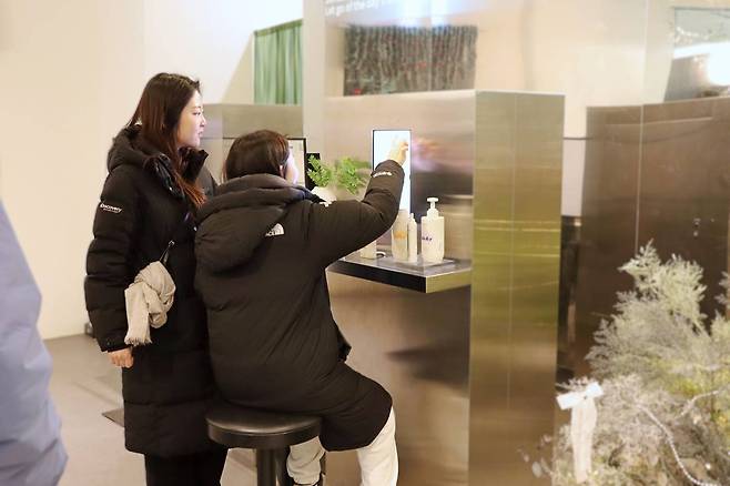 비더비에 방문한 관람객이 직접 AI 뷰티 테크 서비스를 이용하는 모습 / 출처=IT동아