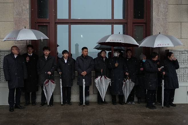 중국 베이징에서 전국인민대표대회사전회의가 열린 가운데 노동자들이 우산을 쓰고 대기하고 있다. 연합뉴스
