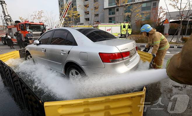 전주시 덕진구 팔복LH아파트 및 더 메이호텔에서 행정안전부를 비롯한 전북소방본부, LH 등이 참여한 가운데 열린 유관기관합동 전기차 화재 대응 제4차 READY Korea 훈련에서 소방대원들이 화재 진압한 전기차를 이동식 소화수조에 넣고 있다. 2024,11,20 ⓒ 뉴스1 김기남 기자