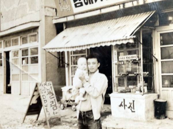 김두수 씨가 사진관 앞에서 아들 김양욱 씨를 안고 사진을 찍고 있다. /남양스튜디오