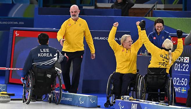 휠체어컬링 이현출(왼쪽)이 13일(현지시간) 이탈리아 코르티나담페초 컬링 올림픽 스타디움에서 열린 2026 밀라노 코르티나 패럴림픽 휠체어컬링 혼성 4인조 스웨덴과의 동메달 결정전에서 패한 뒤 상대와 악수를 하 있다. 사진 | 코르티나=사진공동취재단