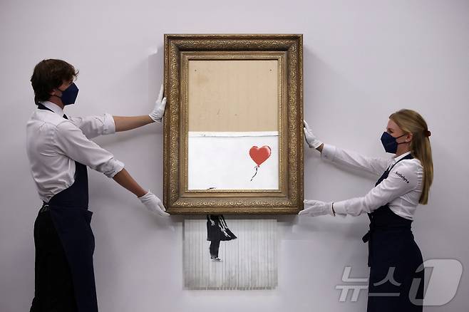 뱅크시의 작품인 '풍선과 소녀'. 2018년 런던 소더비 경매에서 약 100만파운드(당시 약 16억원)에 낙찰된 직후 경매장에서 원격 조종을 통해 스스로 파쇄되는 충격적인 장면을 연출하며 더욱 유명해졌다. 이로 인해 '사랑은 쓰레기통에'(Love is in the Bin)라는 새로운 이름도 붙었다. 이후 3년 뒤인 2021년 다시 경매에 나와 19배에 가까운 약 1900만파운드(약 300억원)에 낙찰됐다. ⓒ 로이터=뉴스1