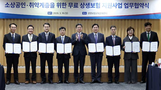 16일 서울 종로구 생명보험교육 문화센터에서 열린 소상공인ㆍ취약계층을 위한 무료 상생보험 지원사업 협약식에서 이억원 금융위원장(가운데)과 6개 지자체 부지사들이 협약서를 들고 기념촬영을 하고 있다. 연합뉴스