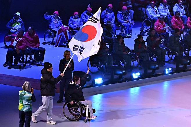 휠체어컬링 백혜진과 스노보드 이제혁이 15일(현지시간) 이탈리아 코르티나담페초 컬링 올림픽 스타디움에서 열린 2026 밀라노 코르티나 패럴림픽 폐막식에서 태극기를 들고 입장하고 있다. 코르티나 | 사진공동취재단