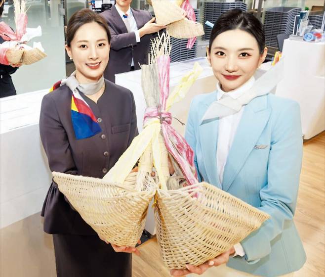 설 연휴를 앞둔 지난달 10일 대한항공과 아시아나항공의 직원이 양사의 화합을 바라는 복조리를 함께 선보였다. 전례가 없는 거대 항공사 간 통합을 진행 중인 두 회사는 ‘카트 미는 법’과 같은 세세한 통합 작업까지 하나씩 점검·추진하고 있다. /대한항공