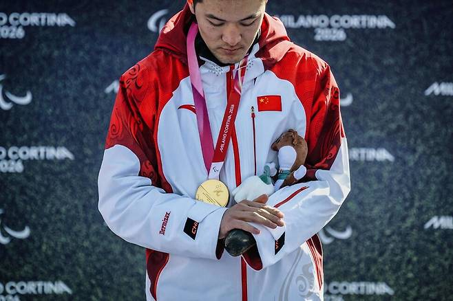 2026년 3월8일 2026 밀라노·코르티나담페초 겨울패럴림픽 남자 스노보드 크로스 SB-UL 우승자인 중국의 지리자가 시상대에서 고개를 숙인 채 자신의 의수를 쓰다듬고 있다. 지리자는 베이징 대회에 이어 두 대회 연속 금메달을 땄다.