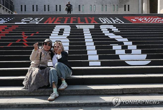 이틀 앞으로 다가온 BTS 공연 (서울=연합뉴스) 김성민 기자 = 그룹 방탄소년단(BTS)의 광화문 공연을 앞둔 19일 서울 종로구 세종문화회관 계단 BTS 홍모물 앞에서 외국인 관광객들이 기념사진을 찍고 있다. 2026.3.19 ksm7976@yna.co.kr