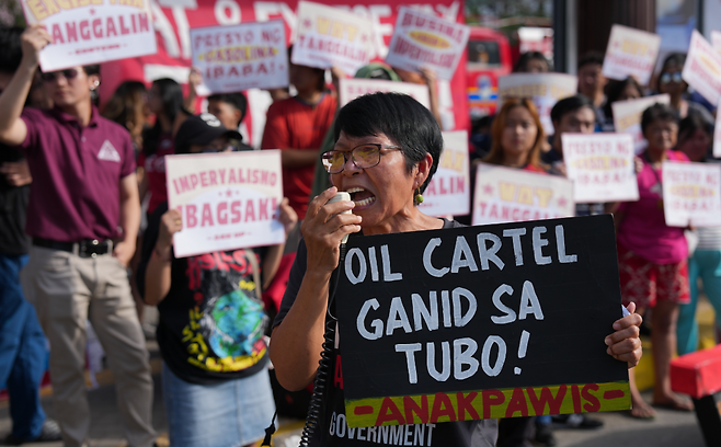 19일 필리핀 케손시티에서 대중교통 지프니(합승차량) 운전기사들이 유가 인하와 운임 인상을 요구하며 파업을 벌이고 있다. 시위자가 ‘이윤에 눈이 먼 석유 카르텔’이라 적힌 피켓을 들고 있다. AP 뉴시스
