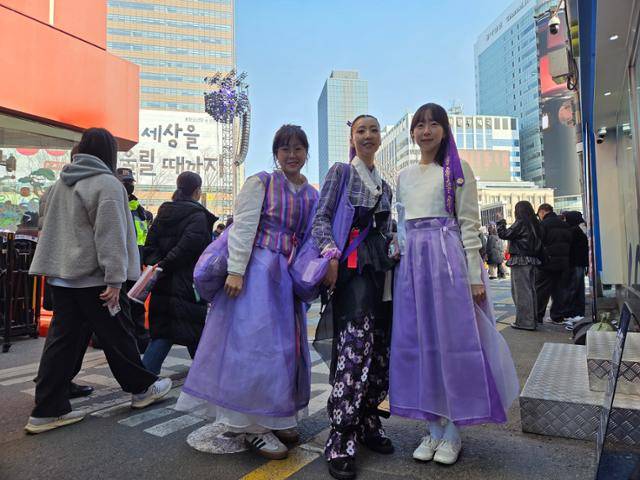21일 서울 광화문광장에서 한복 크리에이터 조은주(왼쪽부터), 신채민, 이현경씨가 BTS 컴백 공연을 보려는 팬들에게 보라색 한복 원단 머리끈을 나눠주고 있다. 남병진 기자