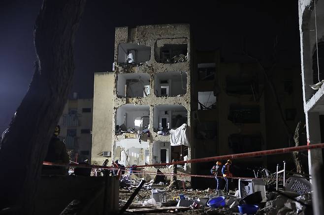 22일(현지시간) 이스라엘 아라드에서 이란 미사일 직격탄을 맞은 현장에서 이스라엘 보안군, 구조대원, 구급대원들이 수습 작업을 벌이고 있다. EPA=연합뉴스