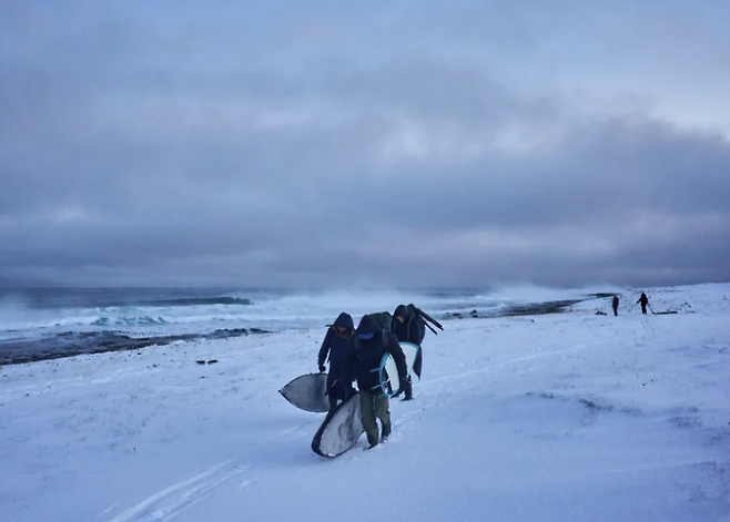 노르웨이 핀마르크 바렌츠해에서 서핑을 마친 서퍼들이 눈과 얼음으로 덮인 해안을 따라 차량이 있는 곳까지 걸어 이동하고 있다. CNN