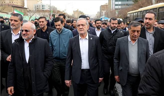 이란 테헤란에서 지난 13일 열린 반이스라엘 집회에 참석한 마수드 페제시키안 대통령(앞줄 가운데)과 그의 아들 유세프 페제시키안(두 번째 줄 푸른 자켓). 이란 국영 언론이 배포한 사진이다. 웨스트아시아뉴스에이전시/뉴욕타임스 누리집 갈무리