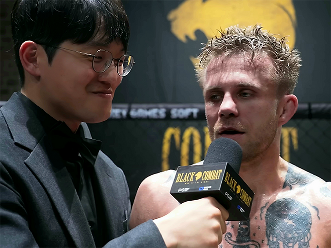 레이크 지가 2026년 3월 경기도 오산시 종합격투기 국가대항전 ‘블랙컵’ 준준결승 밴텀급 경기 후 미국팀 선수로서 승리 소감을 말하고 있다. 블랙컵 첫 시즌은 유튜브 채널 ‘블랙컴뱃’ 유료 멤버십 단독 생중계다. 왼쪽은 김경원 블랙컴뱃 실장 겸 링아나운서. 사진=이데아 파라곤