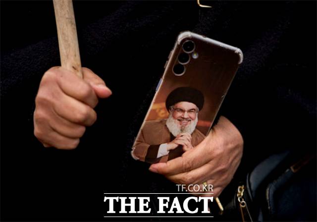 이슬람 공화국 연대 시위에 참가한 한 여성이 사망한 헤즈볼라 지도자 사예드 하산 나스랄라의 사진으로 꾸며진 휴대전화를 들고 있다.