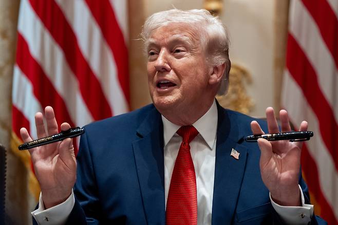 도널드 트럼프 미국 대통령이 26일(현지시간) 백악관 내각 회의 도중 펜 두 자루를 들어 보이고 있다. AP연합뉴스