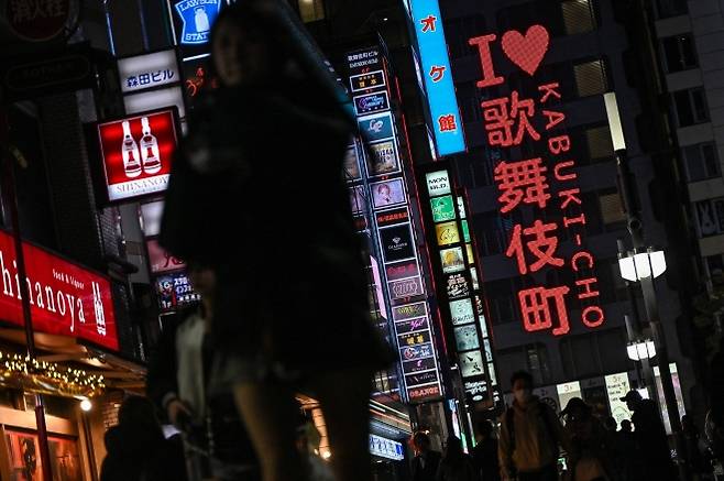 도쿄 신주쿠 구 가부키초의 홍등가 유흥가에 있는 네온사인 옆을 걷는 사람들의 모습. AFP 연합뉴스