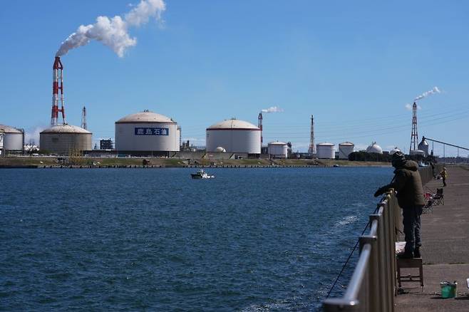 일본 도쿄 동쪽 가미스에서 지난 15일 지역 주민들이 부두에서 낚시를 하는 가운데 에네오스 그룹 가시마 정유공장에서 연기가 나오고 있다. 사진=뉴시스