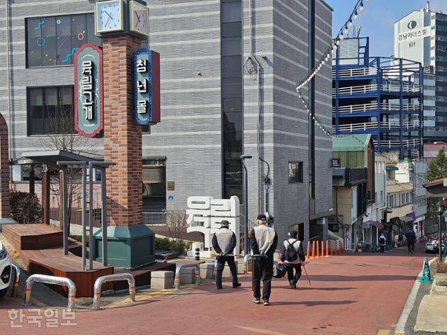 지난달 20일 강원도 춘천 육림고개 청년몰 표지 아래로 노인일자리 근로자들이 지나가고 있다. 춘천=나광현 기자