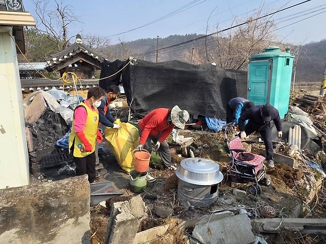 ▲ 3월 30일 의성 비안면에서 위원들이 자루와 양동이를 들고 폐기물을 담아 옮기며 정리 작업을 진행하고 있다. 의성군 제공