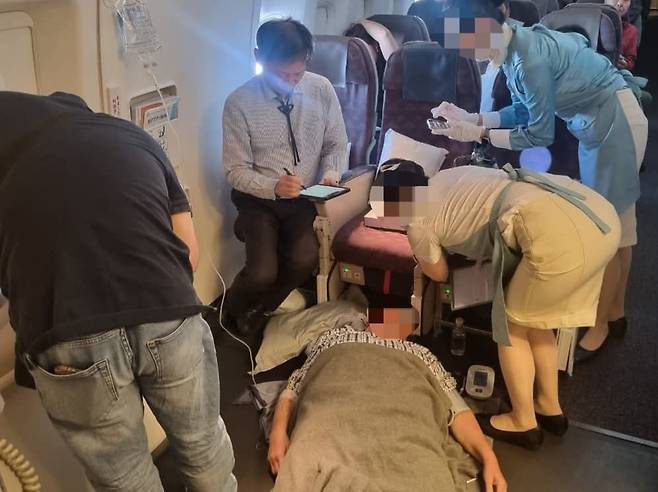 24일 비행기에서 김정환 강남을지병원 교수 등이 응급조치를 하고 있는 상황을 포착한 사진./김정환 강남을지대병원 교수 페이스북