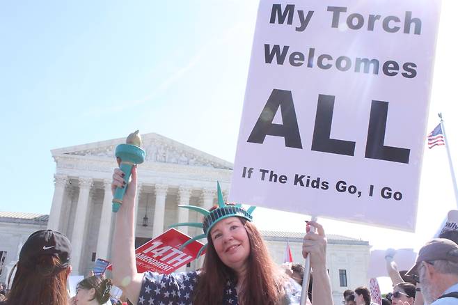 자유의 여신상 복장으로 나온 시위대 (워싱턴=연합뉴스) 백나리 특파원 = 1일(현지시간) 도널드 트럼프 미 대통령의 출생시민권 금지 행정명령이 적법한지를 두고 변론을 연 연방대법원 앞에서 자유의 여신상 복장을 한 시위 참가자가 피켓과 횃불을 들어 보이고 있다. 2026.4.2. nari@yna.co.kr