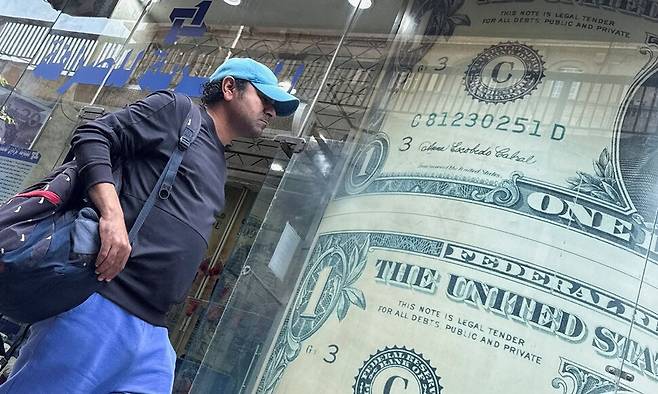 중동전쟁이 길어지면 미국의 재정적자 문제가 또 불거지고 이는 미 국채 신뢰성에 대한 의문을 증폭할 것이다. 2026년 3월9일 이집트 카이로에서 한 남성이 미국 달러 이미지가 표시된 환전소 전광판 앞을 지나가고 있다. REUTERS