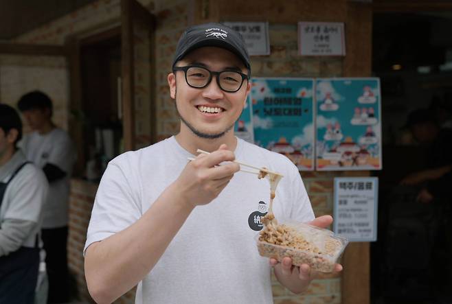 Je Joon-hyuk, owner of Nottodo Natto & Bar, with a pack of his homemade natto at his restaurant near Hyochang Park in Seoul (Tammy Park/The Korea Herald)