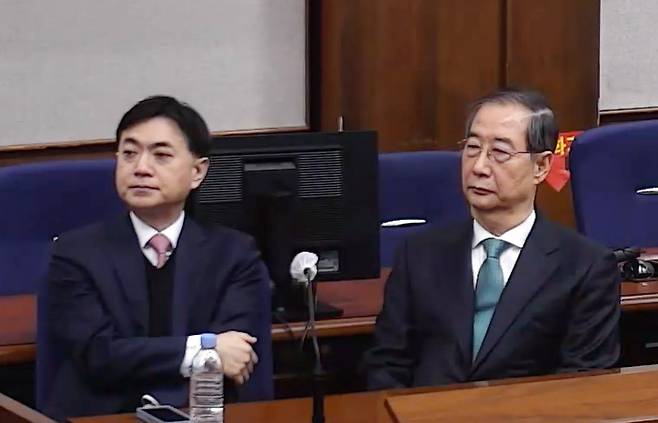 내란 중요임무 종사 혐의를 받는 한덕수 전 국무총리(왼쪽)가 21일 서울중앙지법에서 열린 1심 선고 공판에 출석해 있다. 사진제공=서울중앙지법