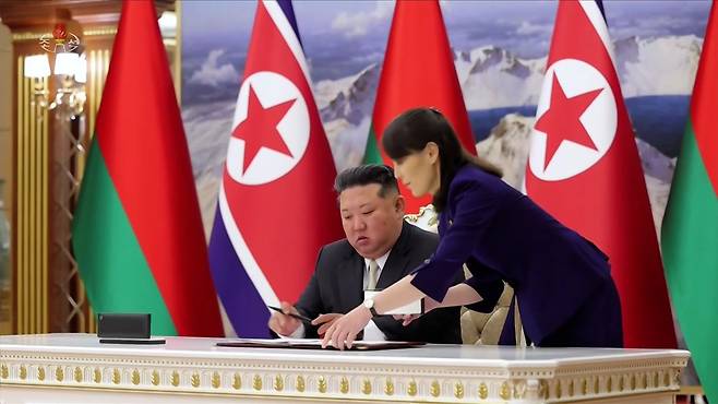 김정은 북한 국무위원장이 지난달 26일 평양에서 알렉산드르 루카셴코 벨라루스 대통령과 양국 간 '친선 및 협조에 관한 조약'에 서명하는 모습. 김여정 당 총무부장이 옆에서 보조하고 있다. 조선중앙TV 캡처, 연합뉴스