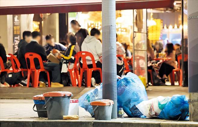8일 저녁 ‘야장 거리’로 바뀐 서울 성북구 성북천 벚꽃길. 고깃집 등 식당 50여 곳이 골목에 테이블을 내놓고 영업 중이다. 식당마다 손님이 북적였다. 벚꽃길 곳곳엔 쓰레기 더미도 쌓여 있다. /박성원 기자
