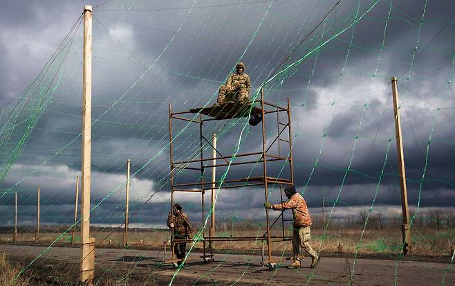 우크라이나 제1221 독립지원대대 소속 장병들이 지난달 3일(현지시간) 동부 도네츠크주 슬로비얀스크 인근 전선 도로에 드론 방어용 그물을 설치하고 있다. EPA=연합뉴스