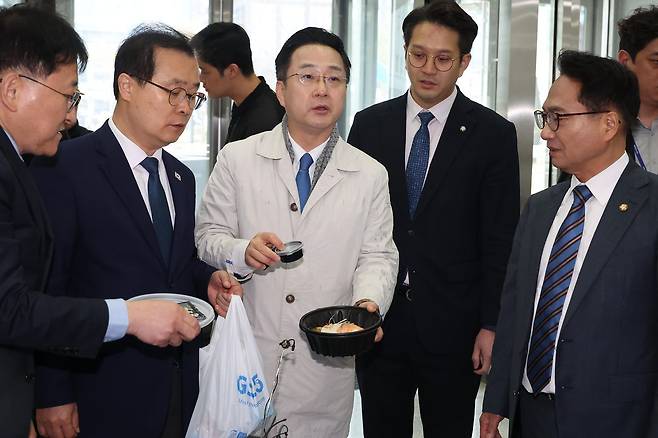 박성준 더불어민주당 의원 등 조작기소 국조특위 의원들이 9일 '연어 술 파티', '진술 회유 의혹' 검증을 위해 경기 수원지검을 현장 방문, 연어회 덮밥을 받아 취재진을 향해 보여주고 있다. 연합뉴스