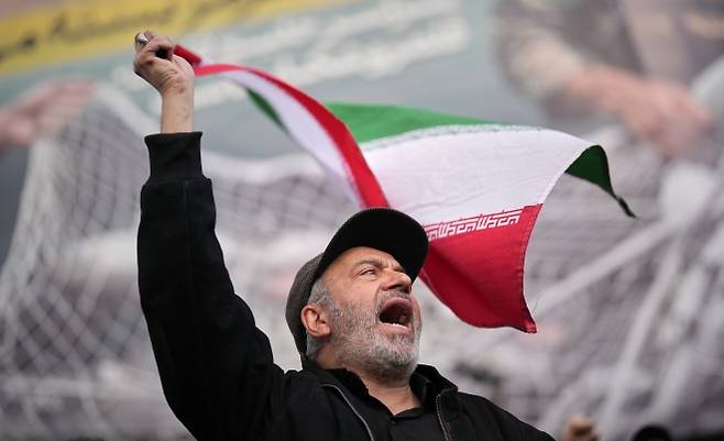 이란의 한 친정부 지지자가 8일(현지시간) 테헤란에서 미국·이스라엘과의 2주 휴전 발표 뒤 열린 집회에서 이란 국기를 흔들며 구호를 외치고 있다. 휴전 이후에도 현지에선 ‘승전’ 분위기가 이어졌다. AP 연합뉴스