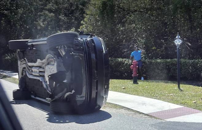 타이거 우즈가 3월 27일 미국 플로리다주 마틴 카운티주피터 아일랜드 인근에서 발생한 교통사고 후 전복된 차량 옆에 서 있다. /사진 AP연합