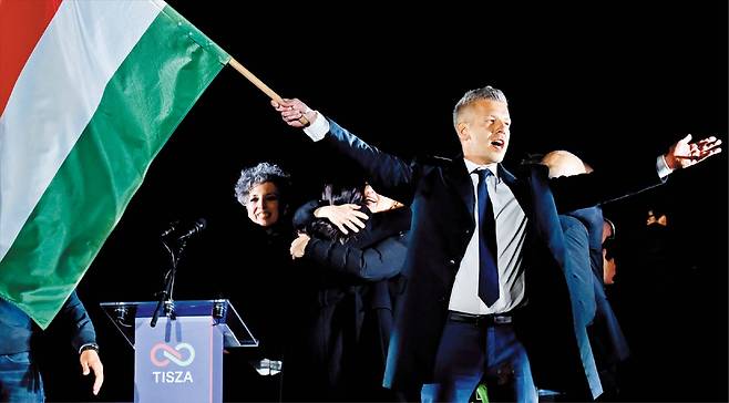 헝가리 총선이 치러진 12일(현지 시각) 수도 부다페스트에서 야당 티서의 마저르 페테르 대표가 지지자들 앞에서 국기를 흔들고 있다. 티서는 이날 전체 199석 중 개헌선인 3분의 2(133석)를 넘는 138석을 확보하며 압승했다. 오르반 빅토르 총리는 이번 패배로 2010년부터 이어진 16년 장기 집권에 마침표를 찍게 됐다. /AP 연합뉴스